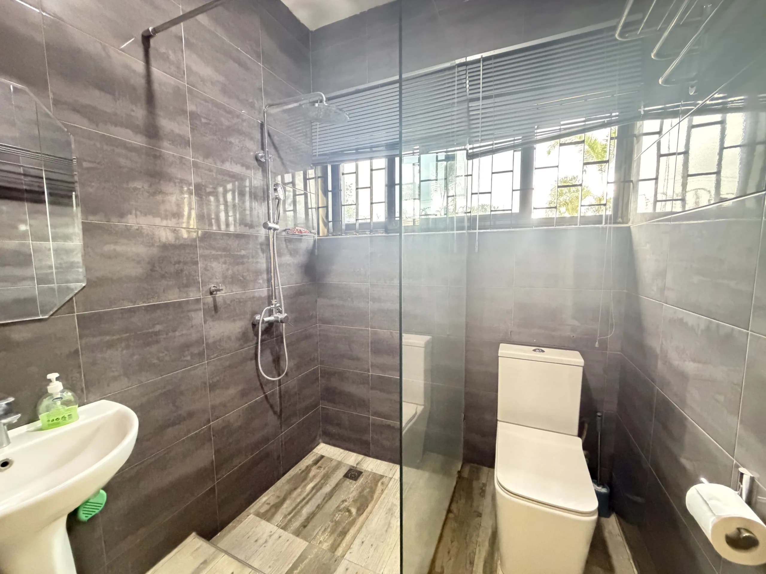 The shower and WC, tiled floor to ceiling in charcoal stone
