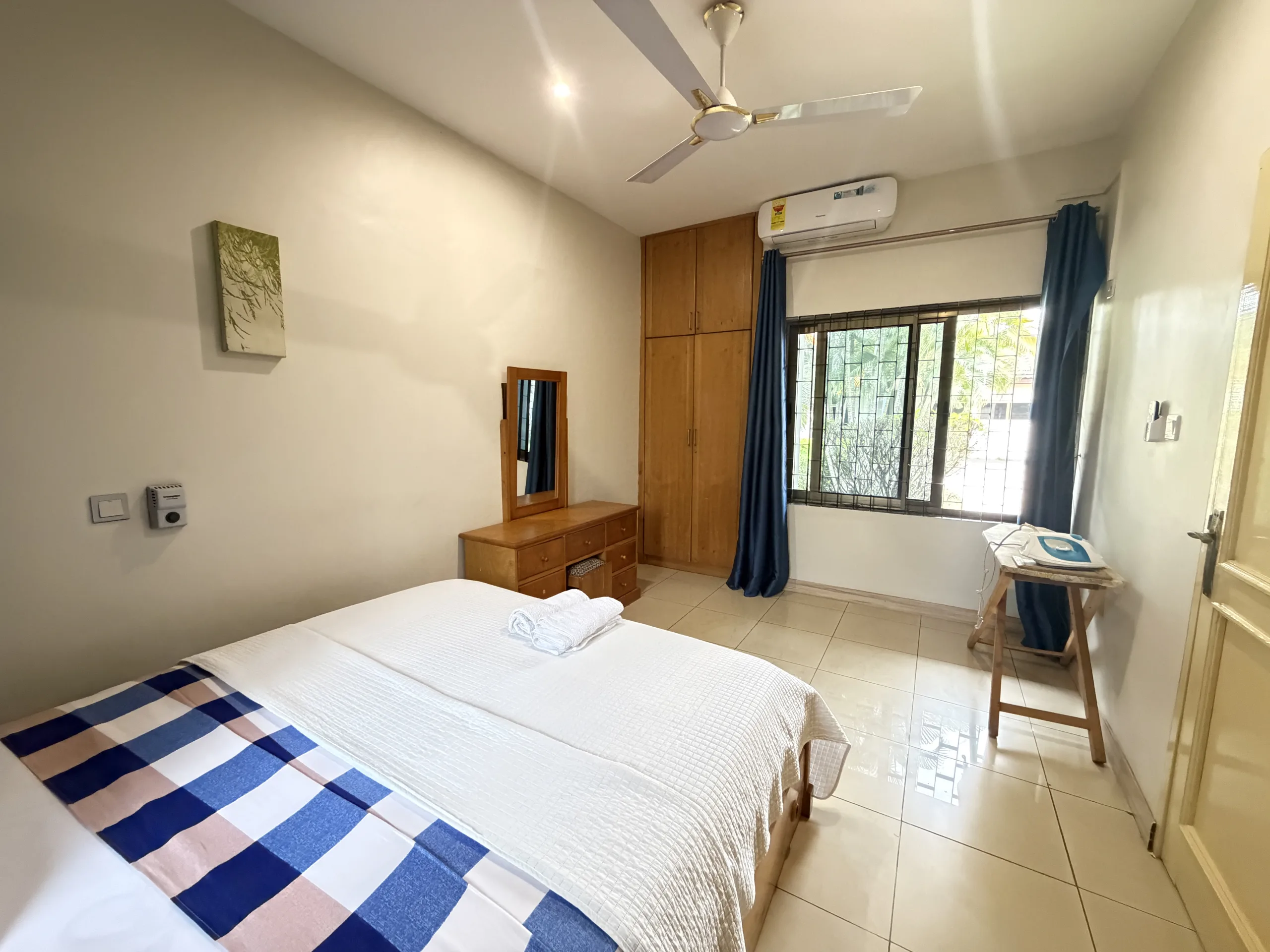 A double bed beside a dressing table, lit from the window