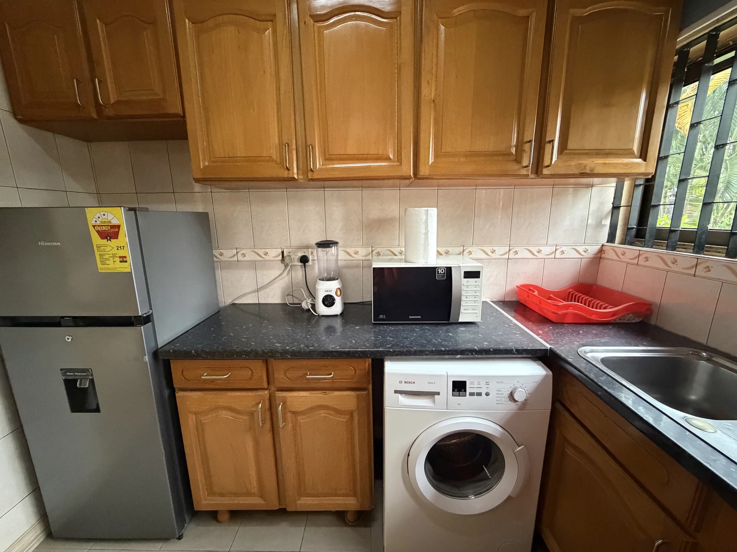 A kitchen with fridge-freezer, microwave and washing machine