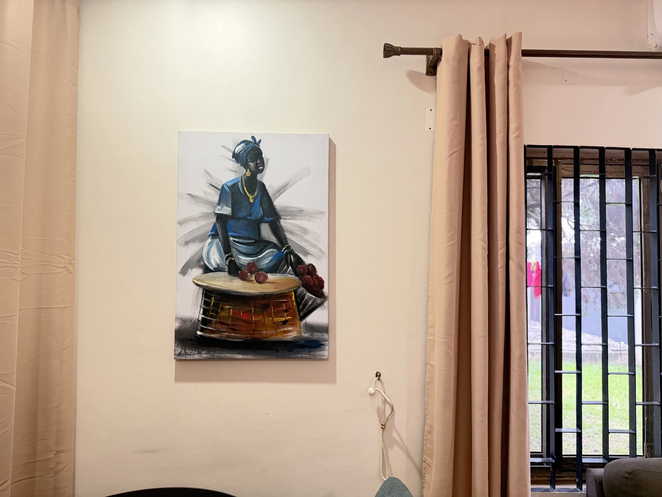 A painting on the living room wall, beside a window looking onto the lawn