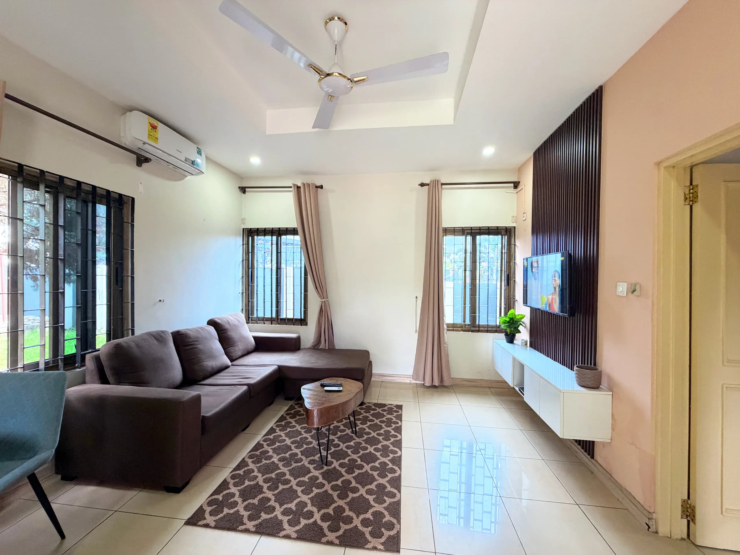 A living room with a brown sofa and wall-mounted television