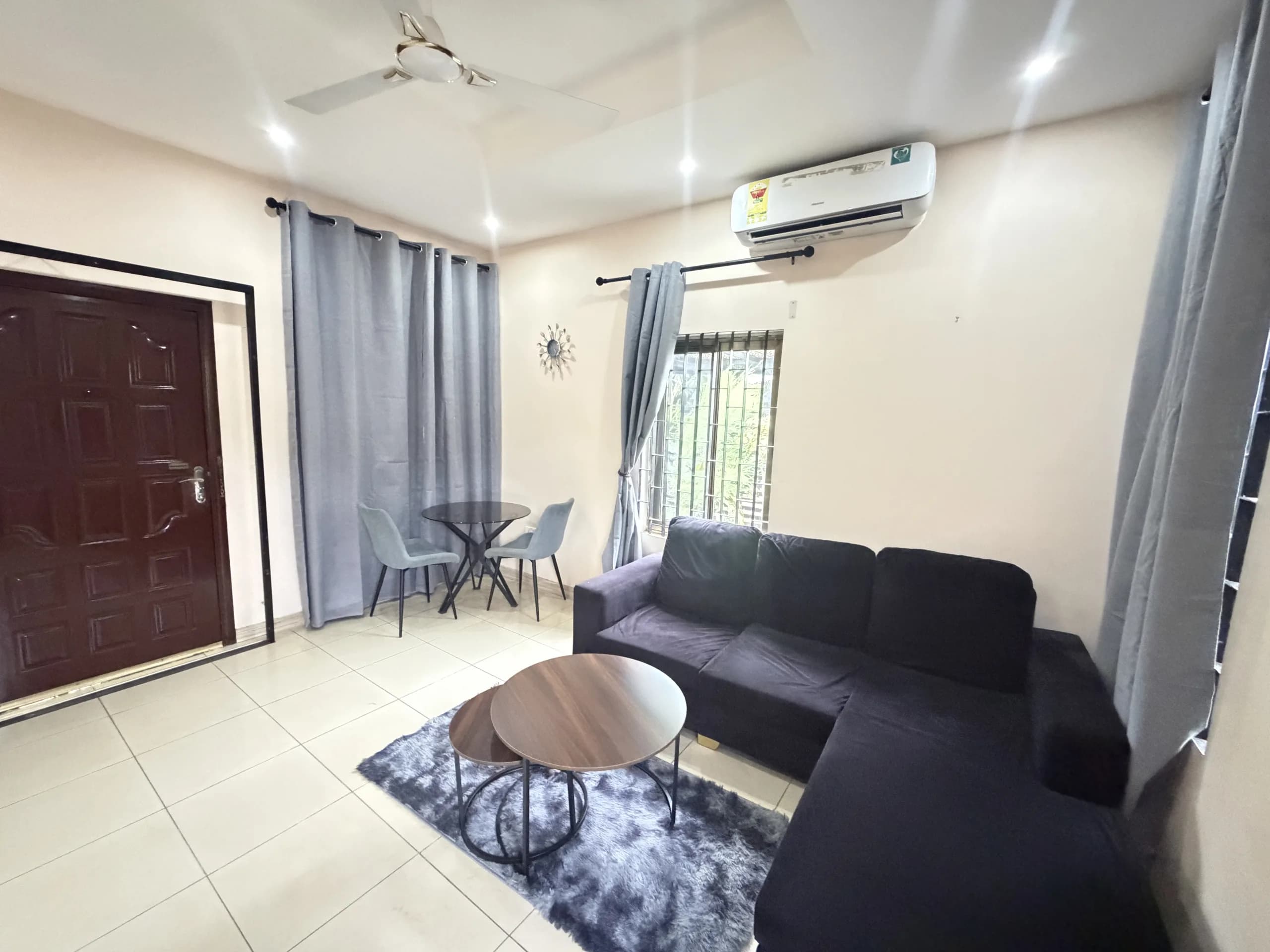 A living room with a charcoal corner sofa, nesting walnut tables and a dining table for two